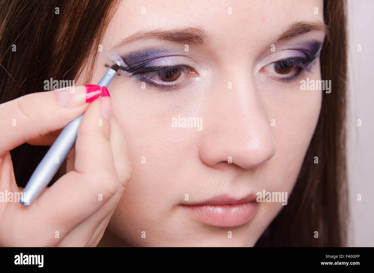 Trauriges Mädchen Make-up Künstler zeichnet Pfeile Stockfoto