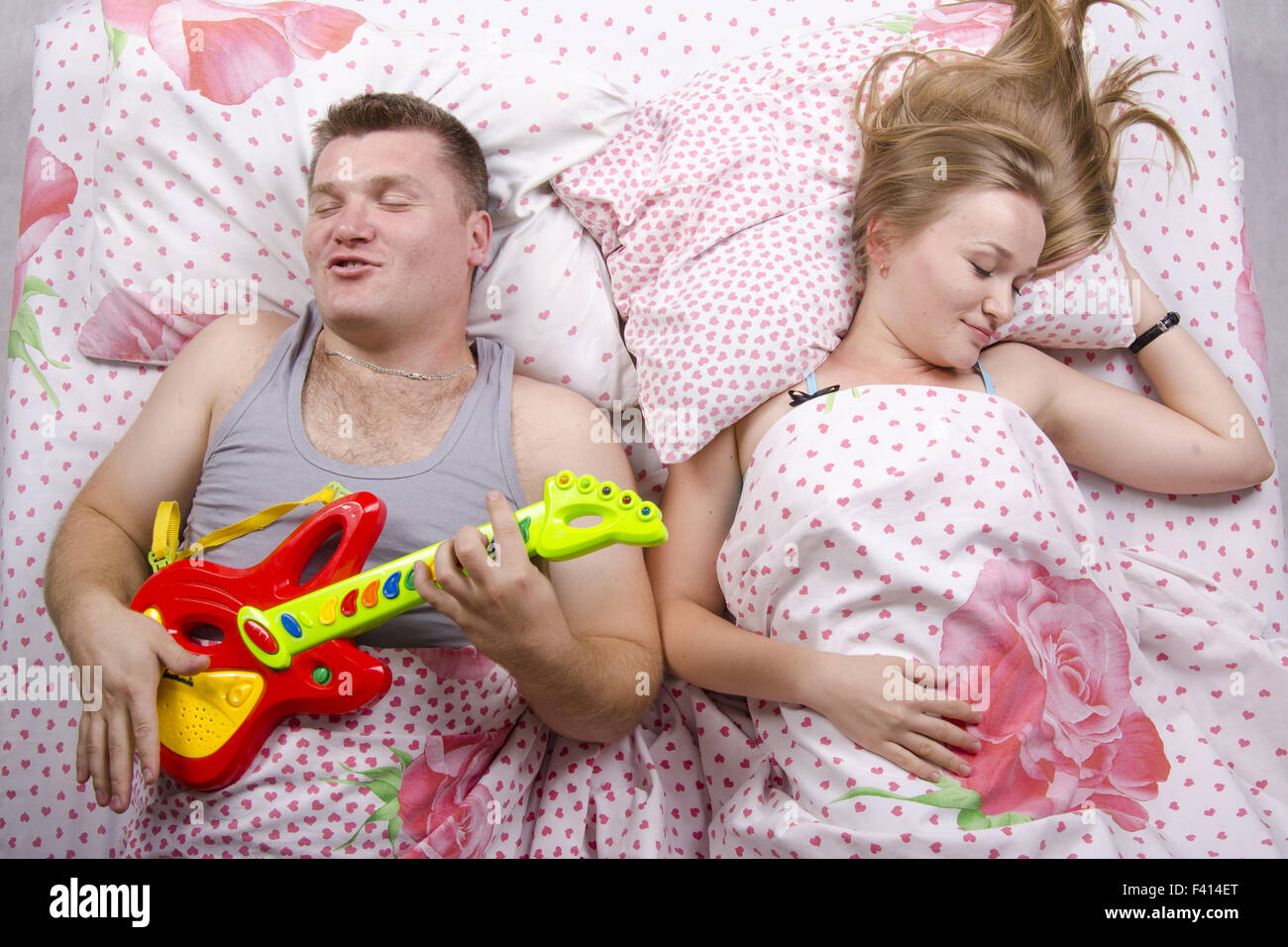 Mann spielt Gitarre, die Frau schläft Stockfoto