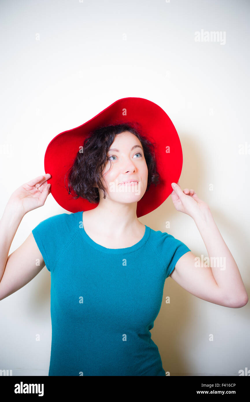 Junge Frau mit roten Hut und blau Kleid posiert nachschlagen Stockfoto