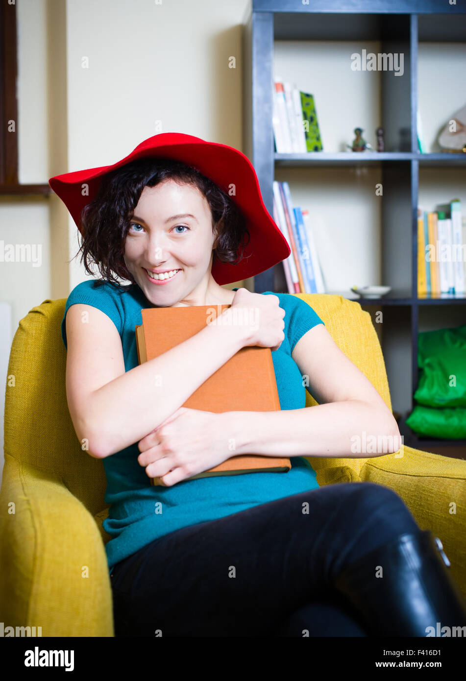 Junge Frau mit roten Hut lächelnd mit einem Buch mit brauner Deckel Stockfoto