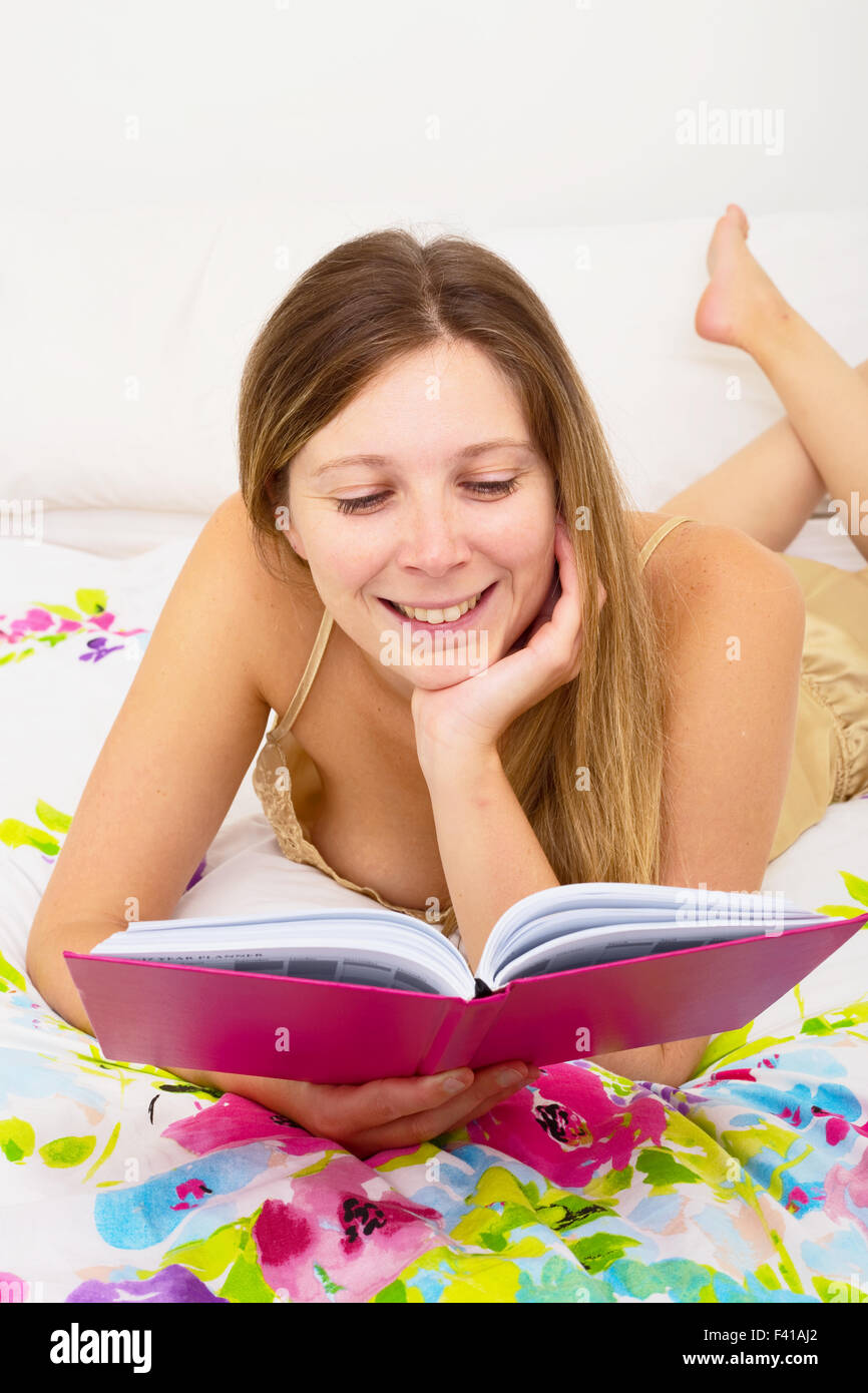 junge Frau im Bett lesen Stockfoto