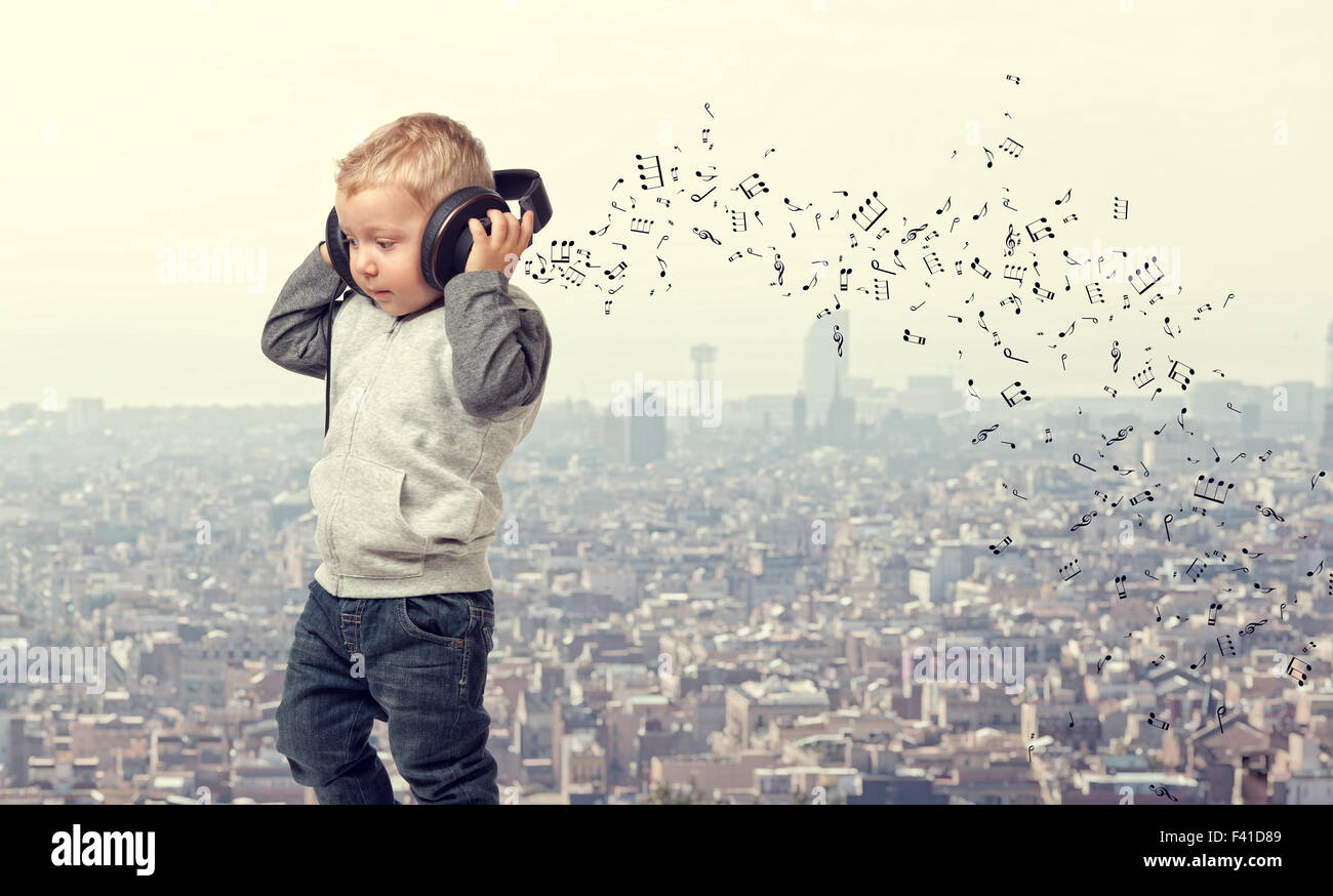 kleines Kind mit Kopfhörer und moderne Stadt Hintergrund Stockfoto