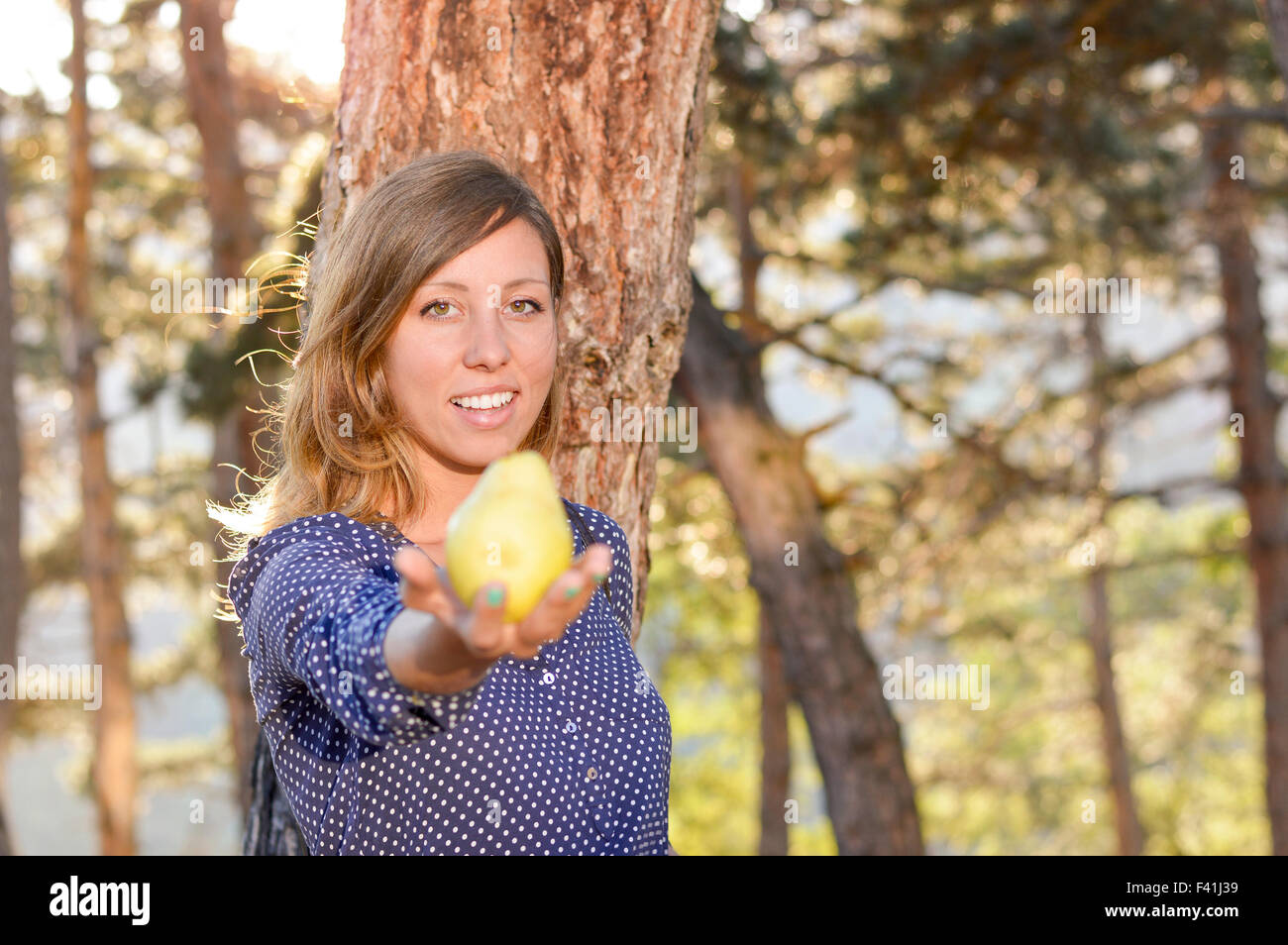 Mädchen hält eine Birne im Park mit Sonnenuntergang im Hintergrund und Objektiv flare-Effekt Stockfoto