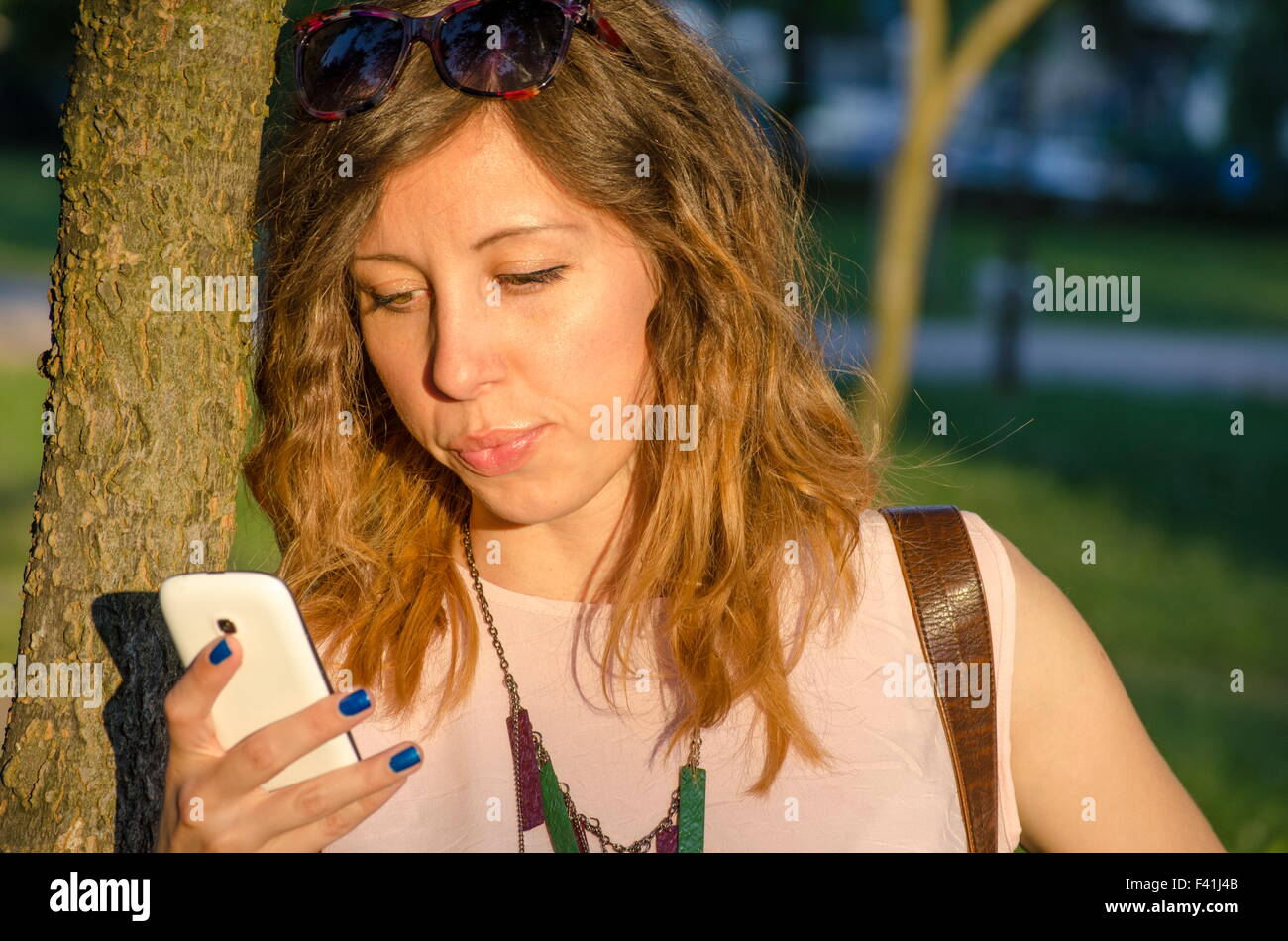 Mädchen mit einem Smartphone mit Sonne im Gesicht Stockfoto