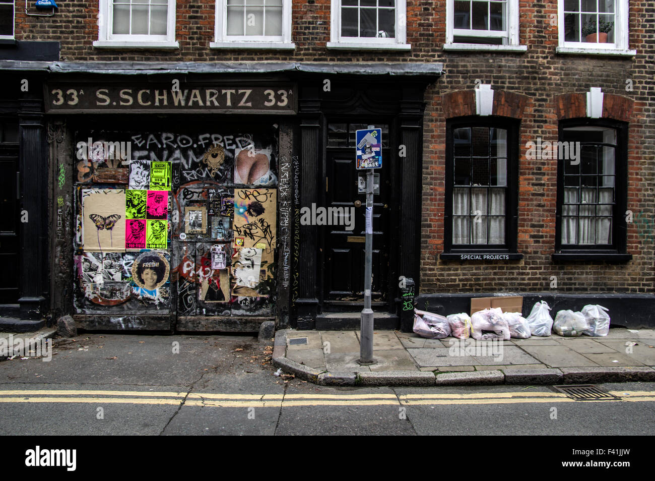 Alter Shop mit Brettern vernagelt und bedeckt mit Plakaten und Graffiti neben Sonderprojekte Schild an einem Fenster über Müllberge Stockfoto