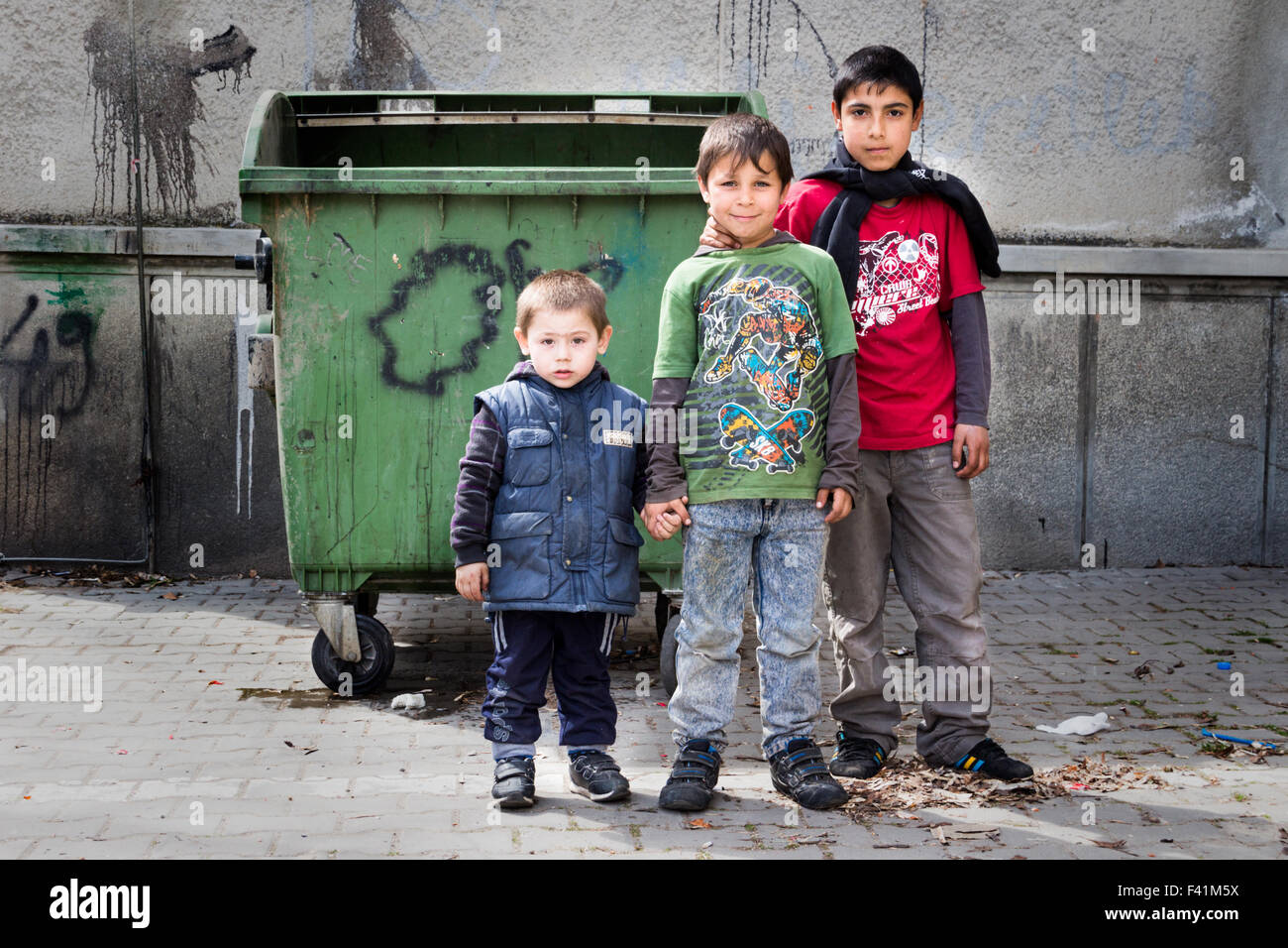 Drei Zigeuner (Roma) jungen stehen vor einem Müllcontainer. Stockfoto
