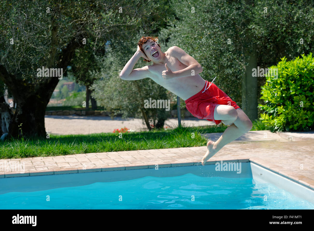 Teenager-Jungen springen in einen Swimmingpool, glücklich Stockfoto
