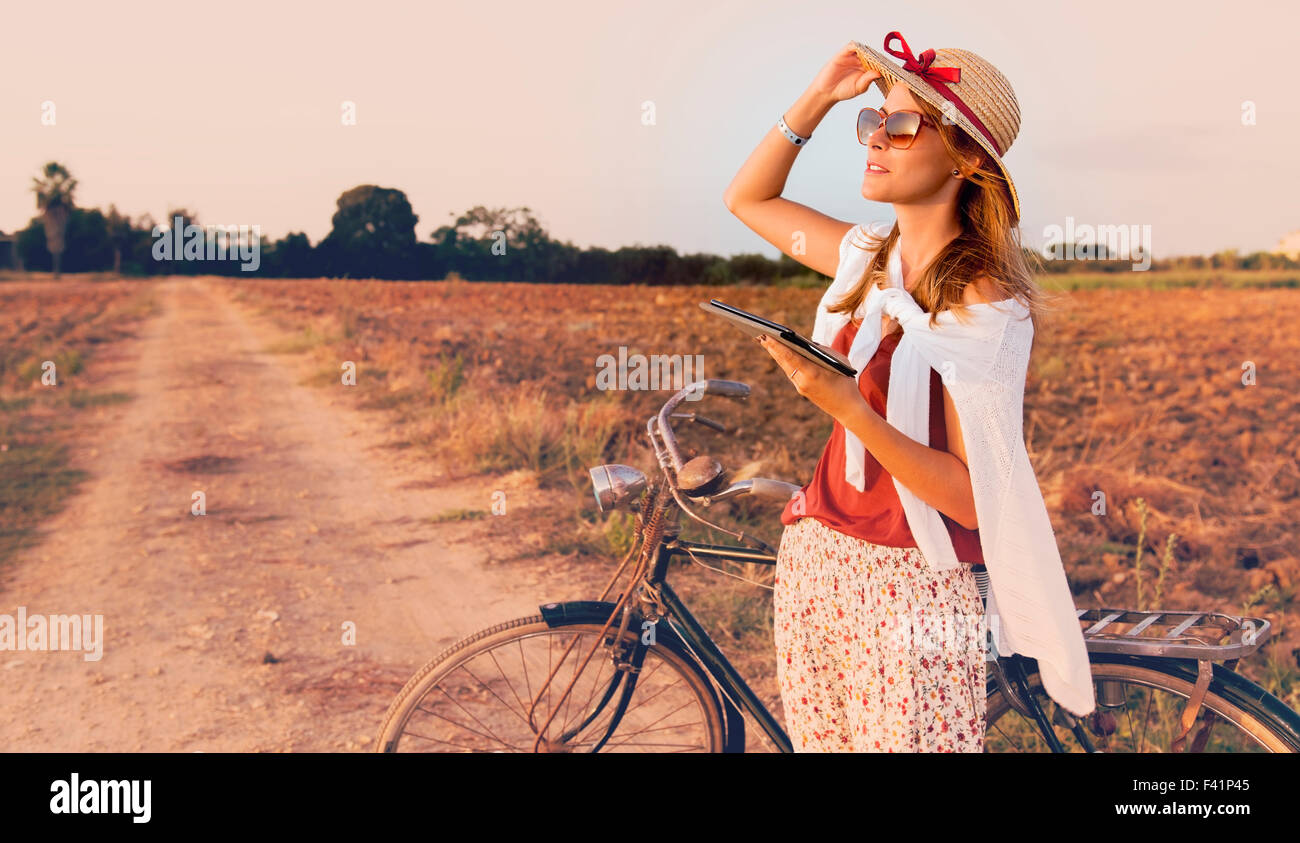 junge Frau mit Fahrrad im Lande arbeiten auf tablet Stockfoto
