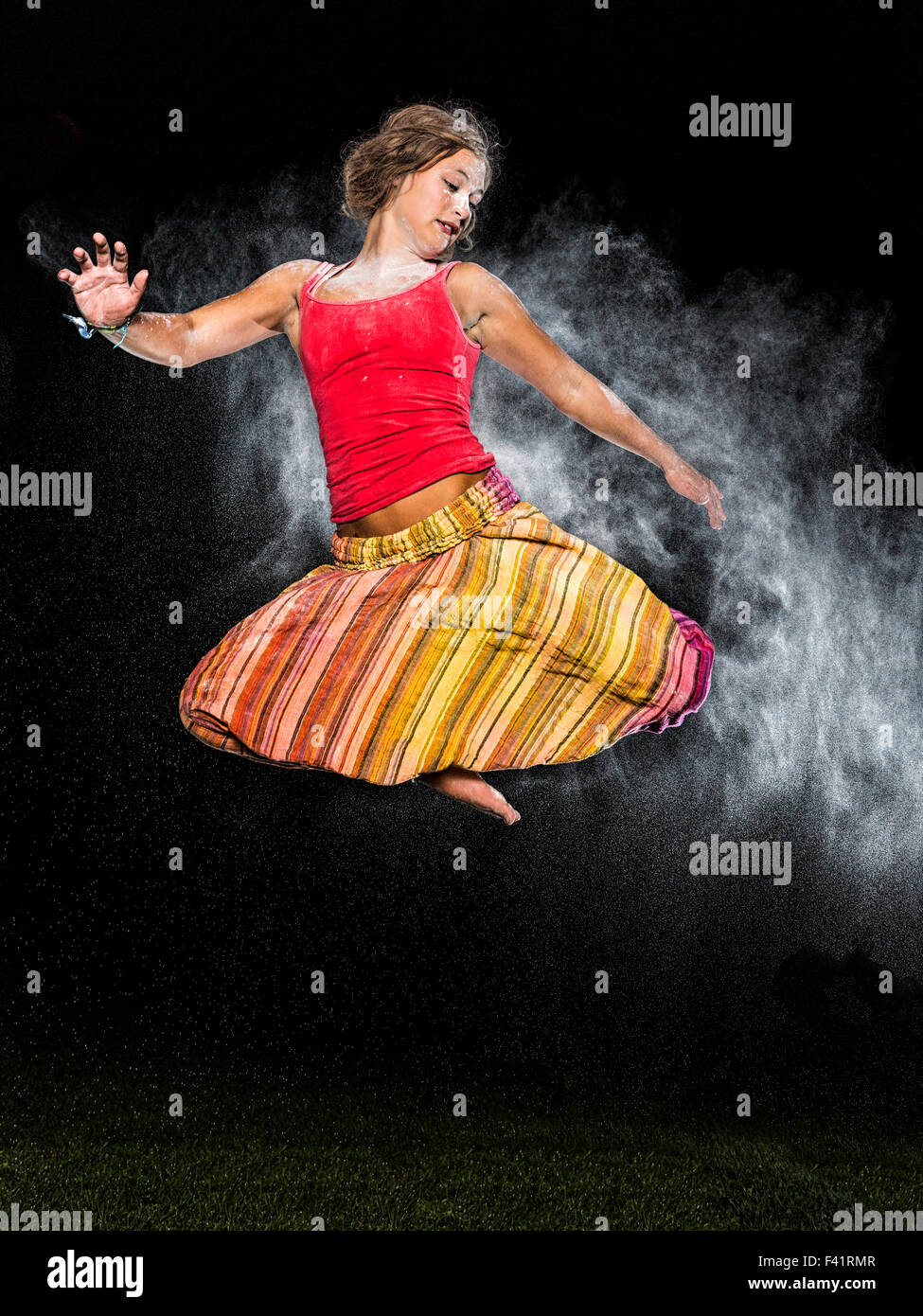 Junge Frau, 19 Jahre alt, springen, in der Luft mit weißer Staub, gegen den Abendhimmel Stockfoto