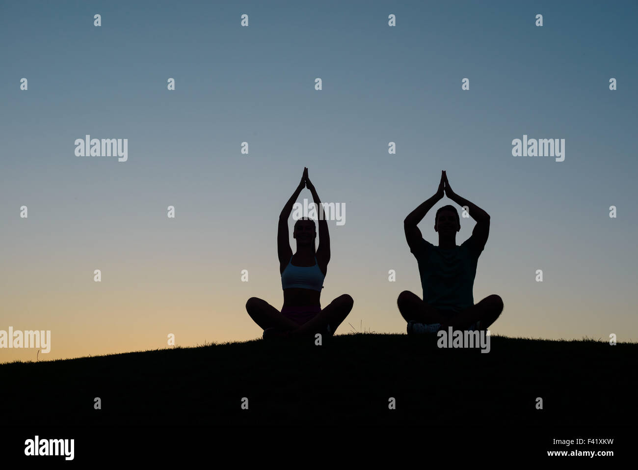 Jungen und Mädchen bei Sonnenuntergang meditieren. Stockfoto