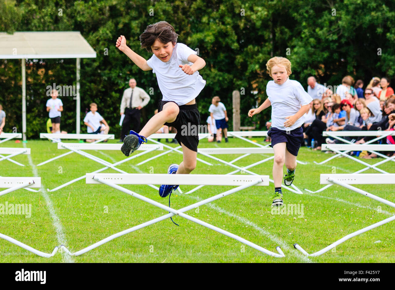 Englisch Schule Sport Tag. Kinder, Jungen, 10-11 Jahre alt, springen über  Hürden während des Rennens, auf Sport im freien Feld, racing in Richtung  Betrachter Stockfotografie - Alamy