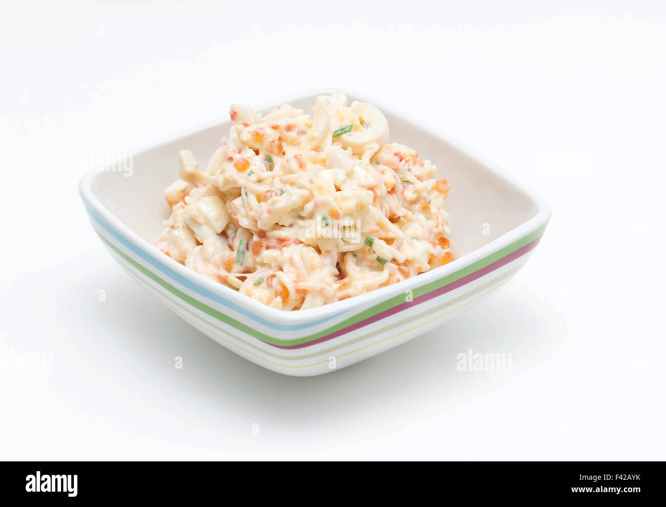 Salat mit Mayonnaise in einer Schüssel auf einem weißen Hintergrund... Stockfoto