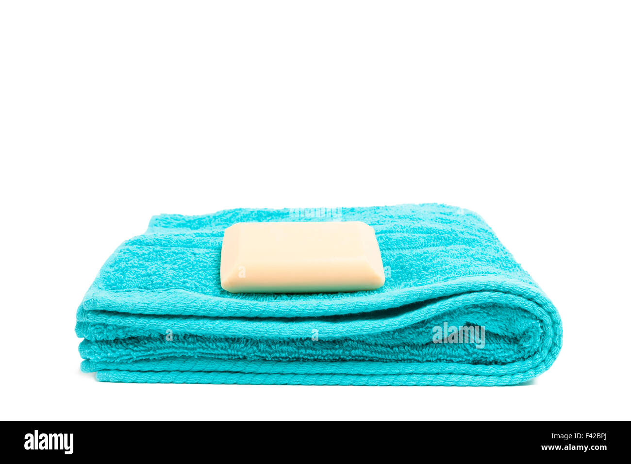 Gefaltetes blaues Handtuch mit Seife von der Seite gesehen und isoliert auf weißem Hintergrund Stockfoto