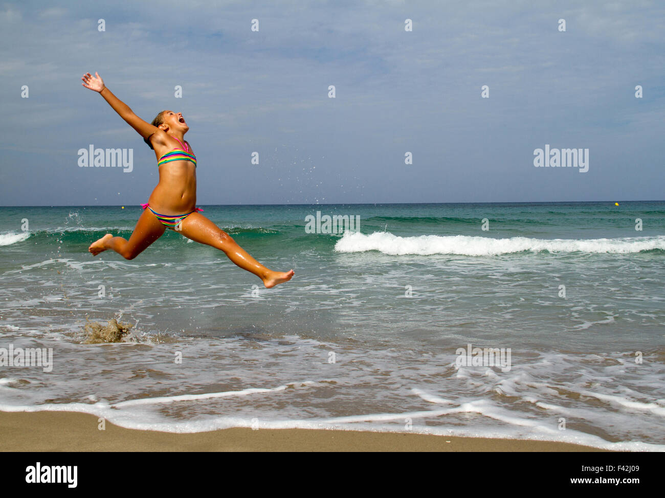 glückliches Mädchen Sprung am Strand Stockfoto