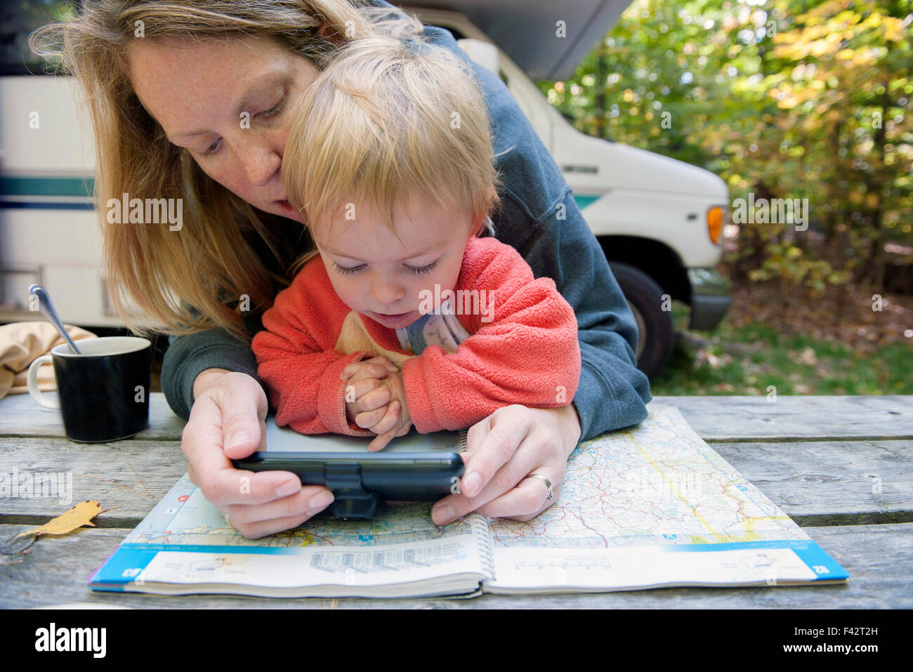 Mutter Holding Kind auf Schoß während der Verwendung von Atlas und GPS, Road-Trip zu planen Stockfoto