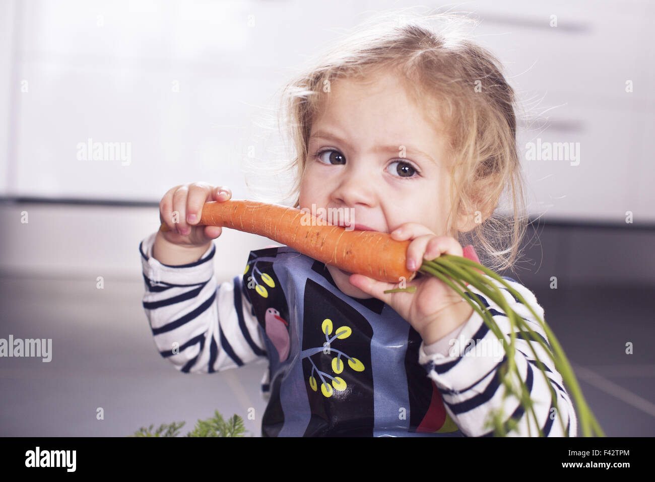Kleine Mädchen essen eine Karotte Stockfoto