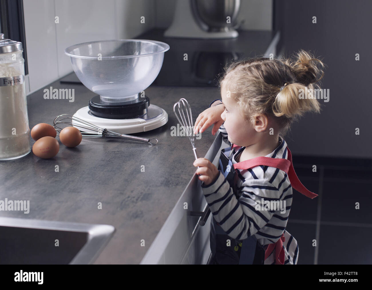 Kleines Mädchen mit Schneebesen in der Küche Stockfoto