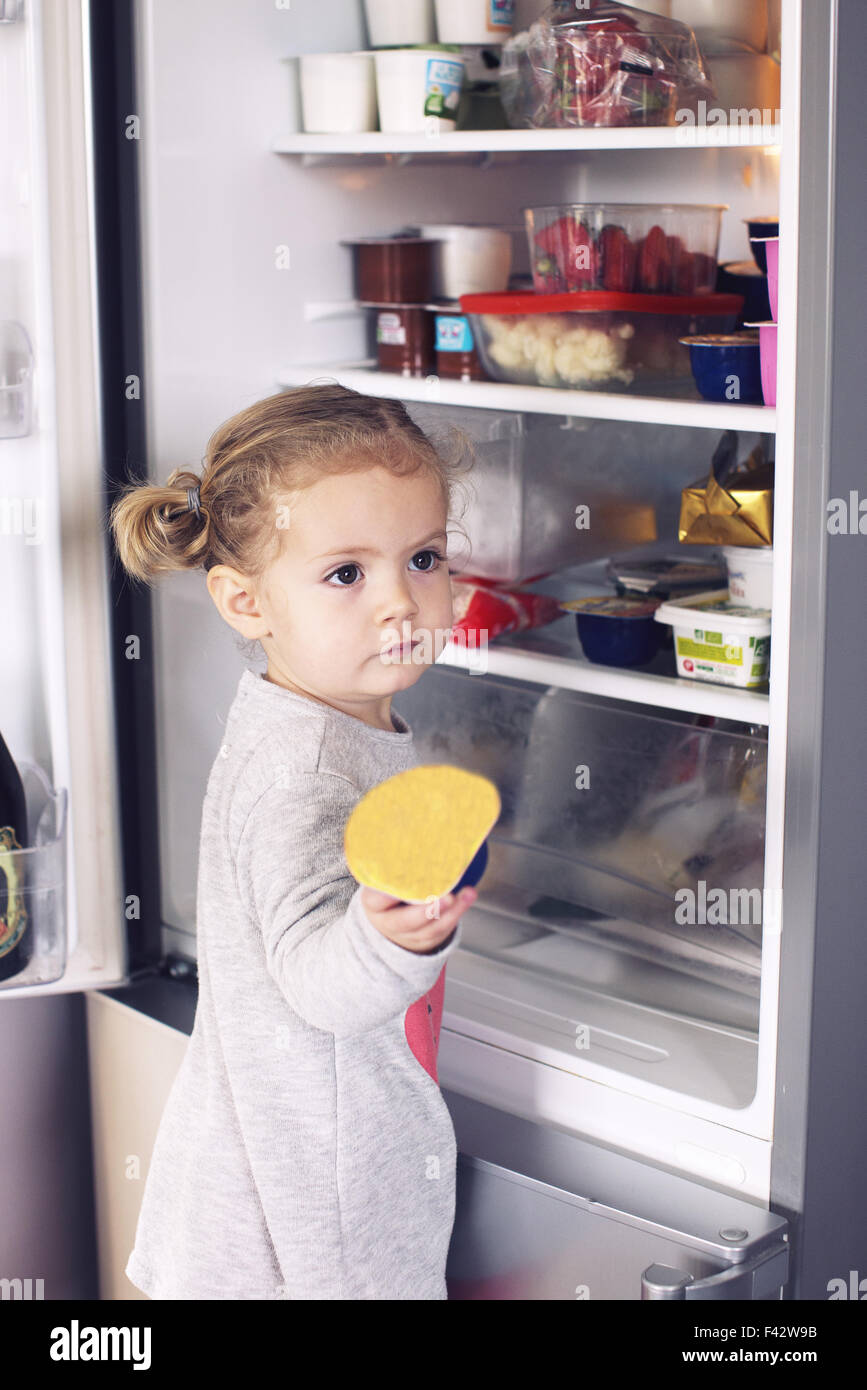 Kleine Mädchen Essen aus Kühlschrank nehmen Stockfoto