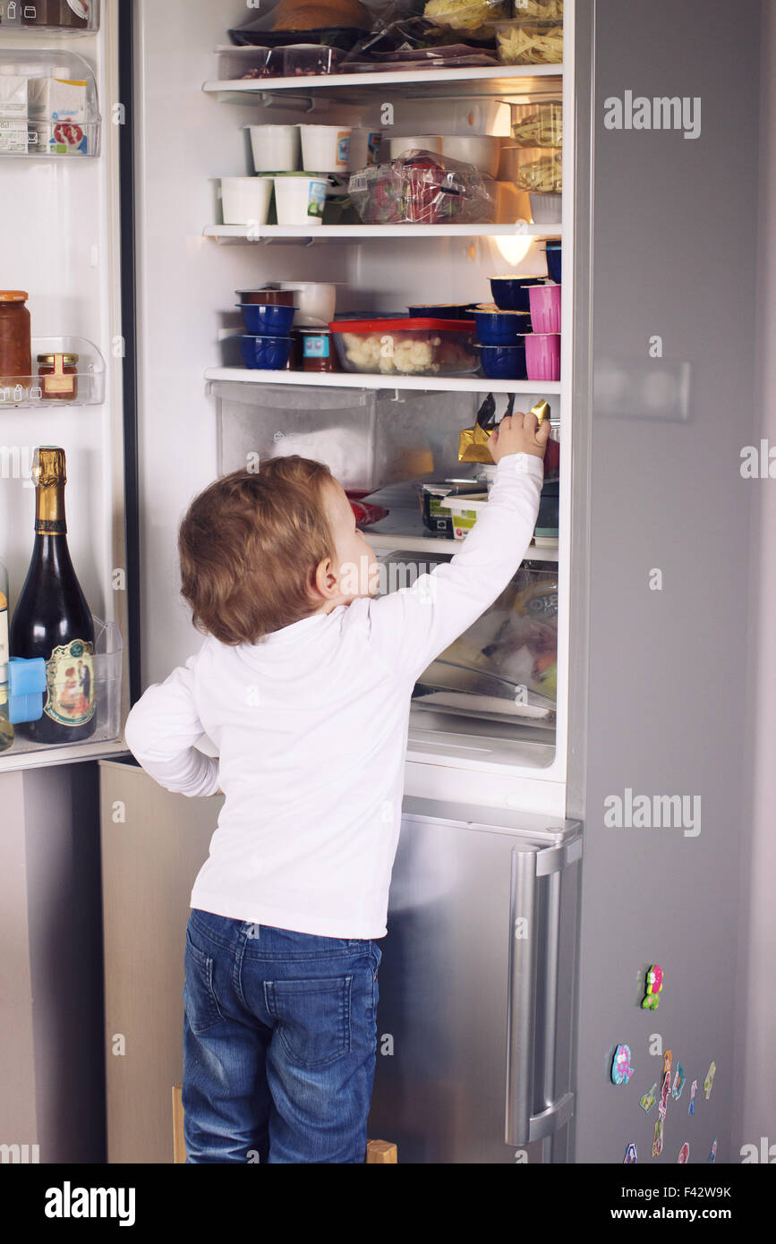 Kleiner Junge Griff nach etwas im Kühlschrank Stockfoto