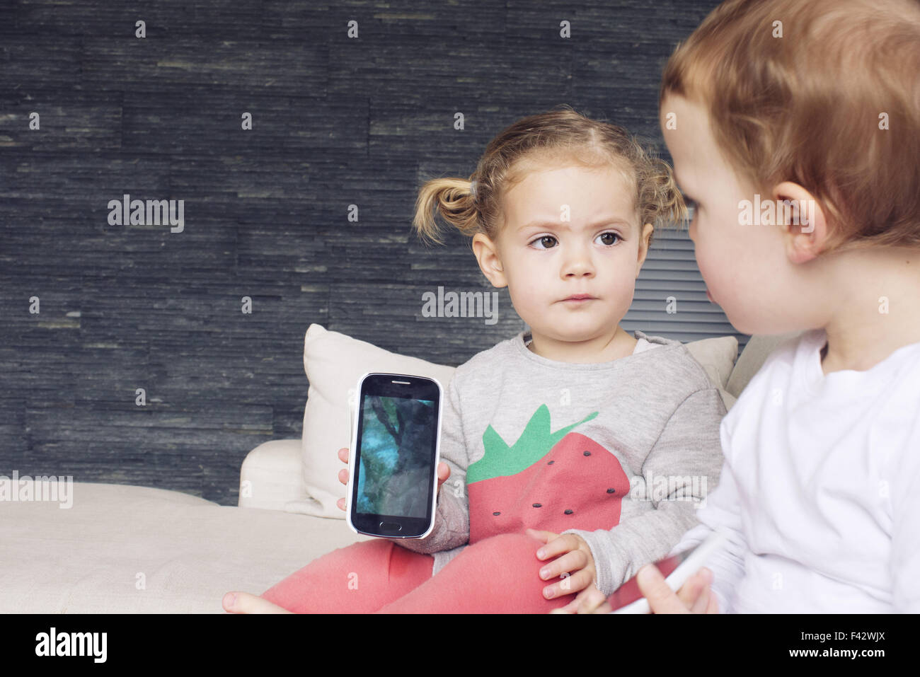 Kleine Mädchen zeigen Smartphone an ihren Bruder Stockfoto