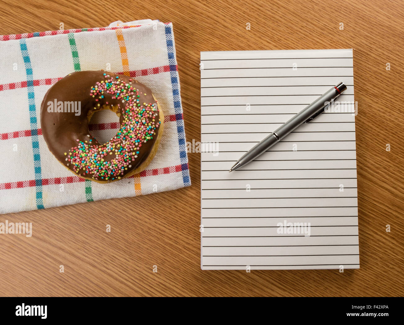 Donut und Notizblock mit Stift Stockfoto