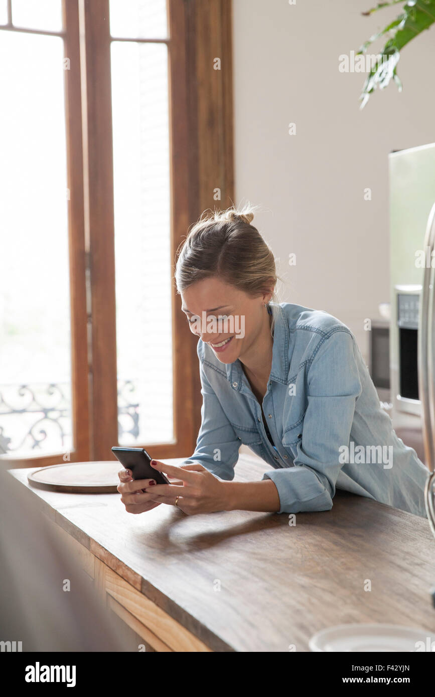 Junge Frau mit Smartphone in Küche Stockfoto
