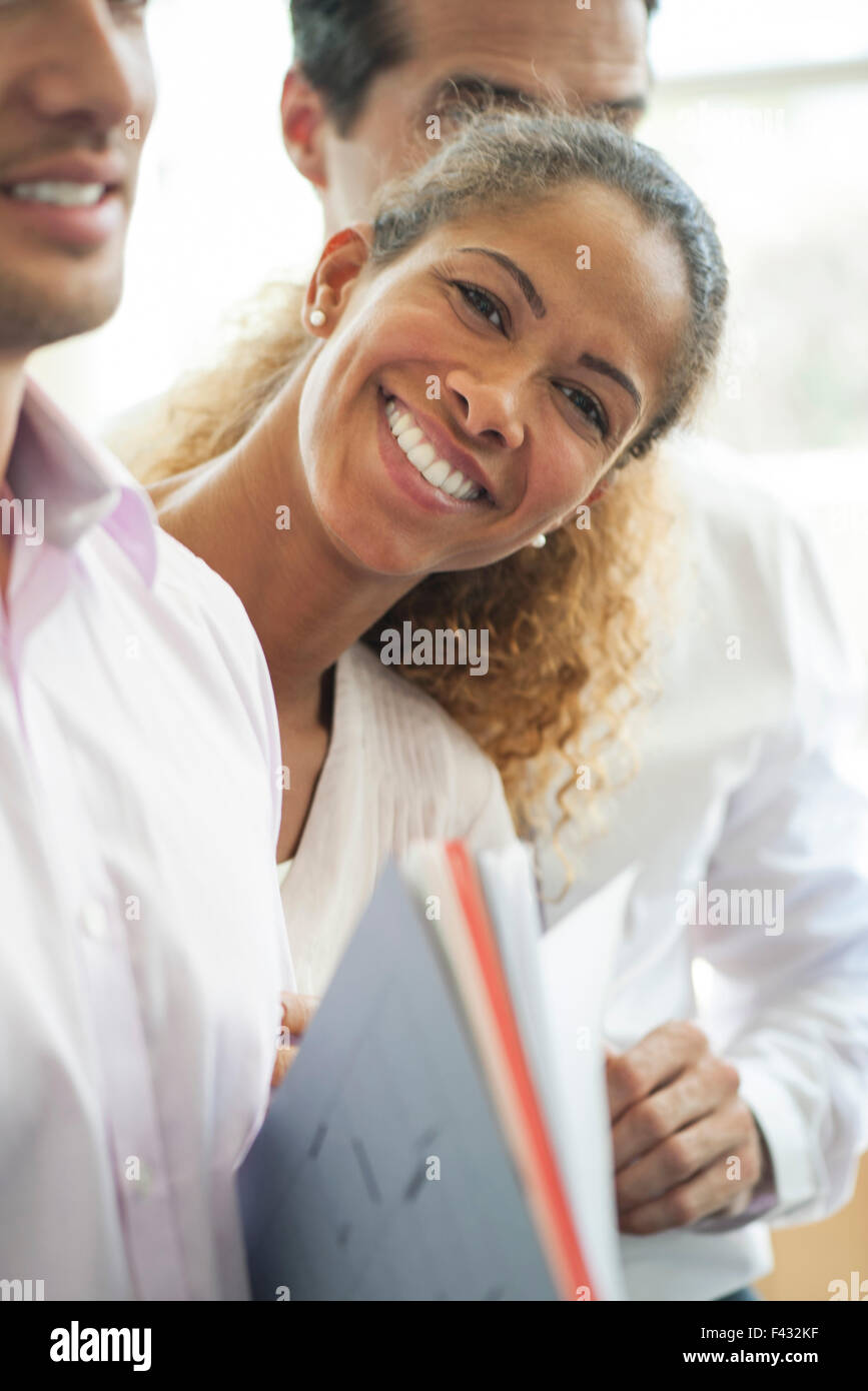 Geschäftsfrau gelehnt zwischen zwei Kollegen, fröhlich lächelnd Stockfoto