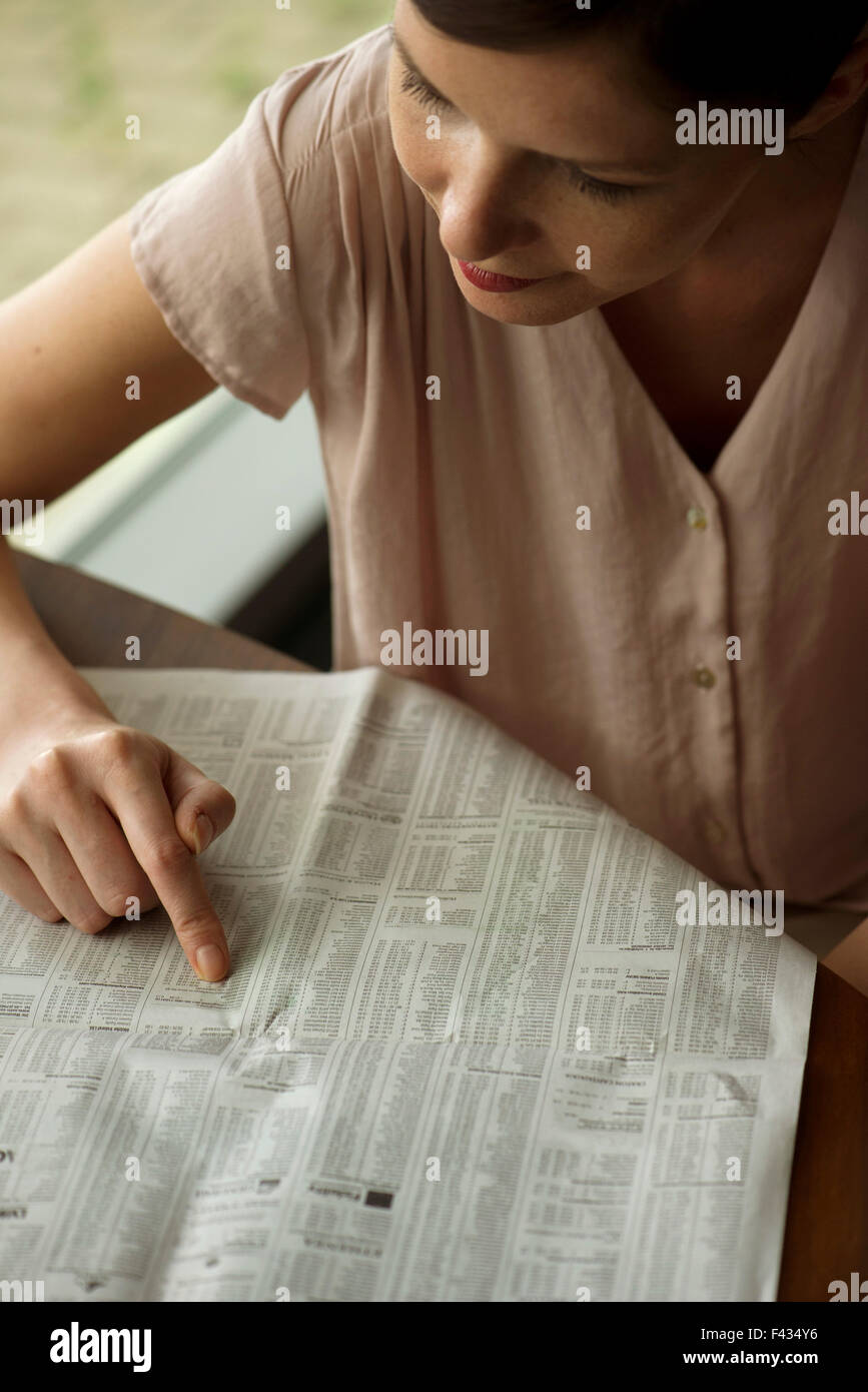 Frau shopping für real Estate in Zeitung Kleinanzeigen Stockfoto