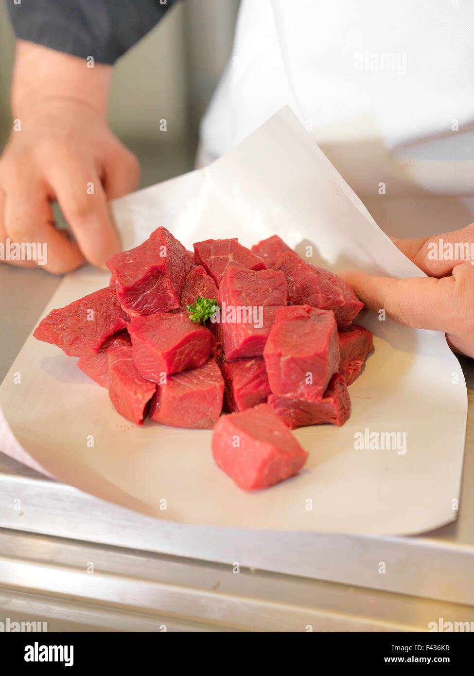 Metzger, wickelte Fleischwürfel in Wachspapier, beschnitten Stockfoto