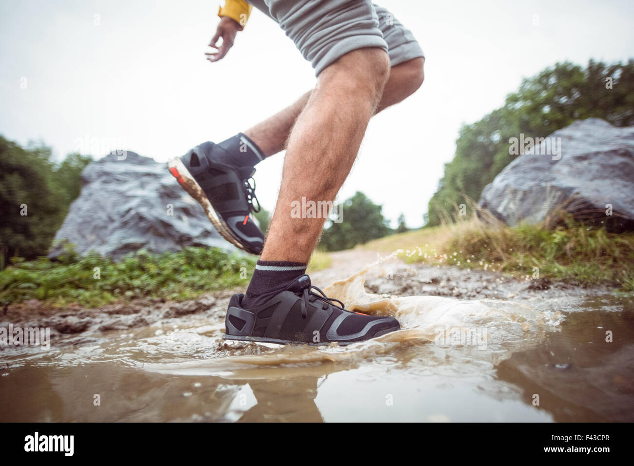 Mann im schlammigen Pfützen plantschen Stockfoto