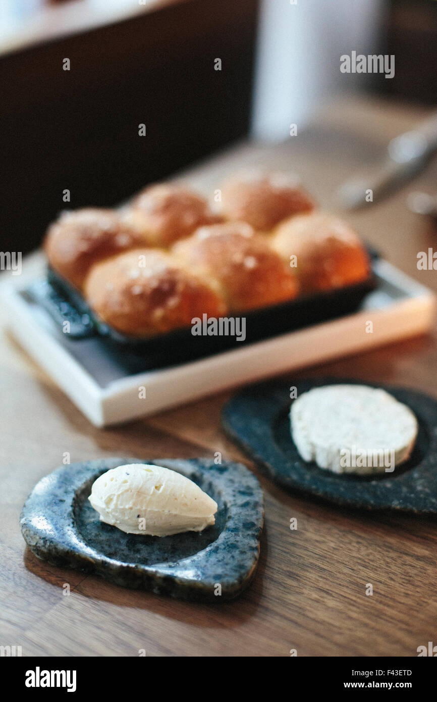 Ein Tablett mit frisch gebackenen Brötchen und Käse auf einer Tischplatte in einem Stadtrestaurant. Stockfoto