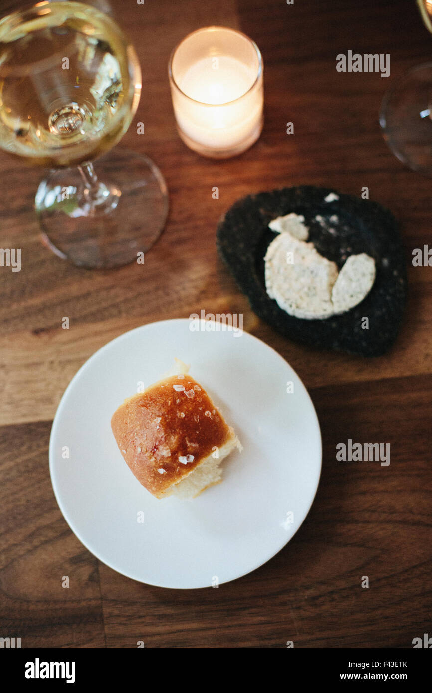 Teller mit Brötchen, Kräuterbutter und Glas Wein in einem Stadtrestaurant. Stockfoto