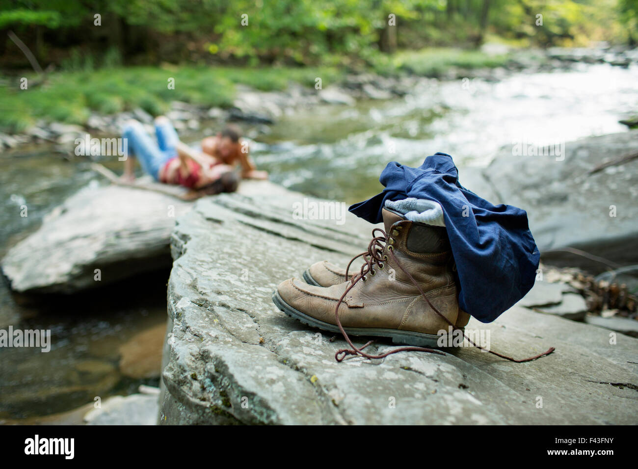 Ein junger Mann und eine Frau auf den Felsen am Ufer eines Flusses. Jeans und Stiefeln auf einem Felsen. Stockfoto