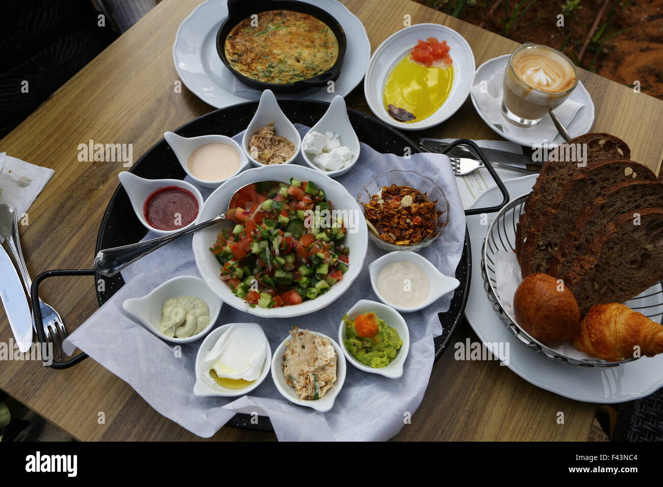 Traditionelle israelisches Frühstück Omelett, Käse, Salate, ein frisches Brötchen und eine Tasse cappuccino Stockfoto