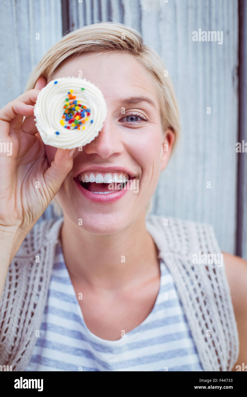 Hübsche blonde Frau mit Cupcake Grimassieren Stockfoto