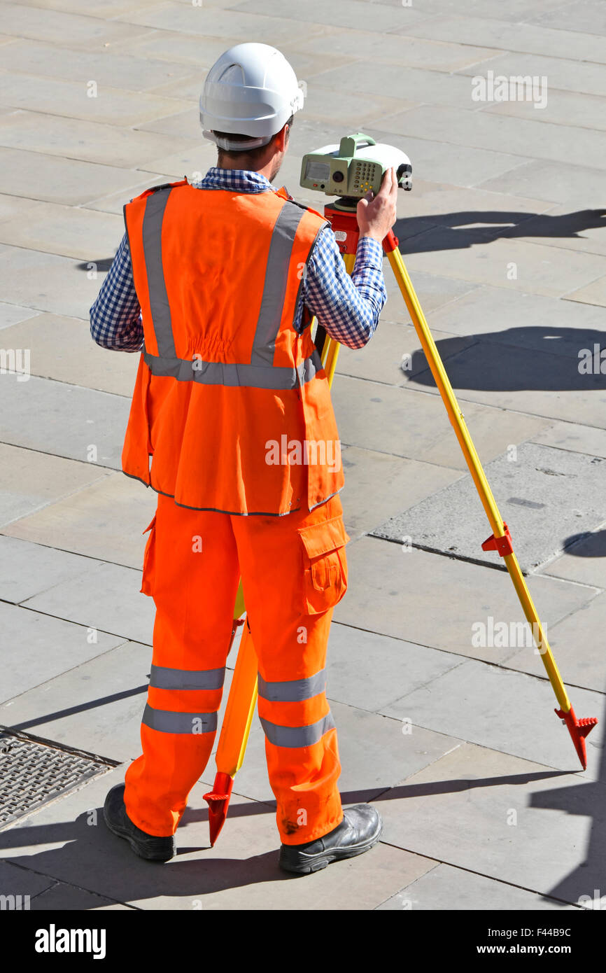 Landvermesser auf öffentlichen Bürgersteig mit Stativ montiert Vermessungsgeräte mit hohen Vis Weste & Arbeitshelm Firmennamen entfernt London England UK Stockfoto