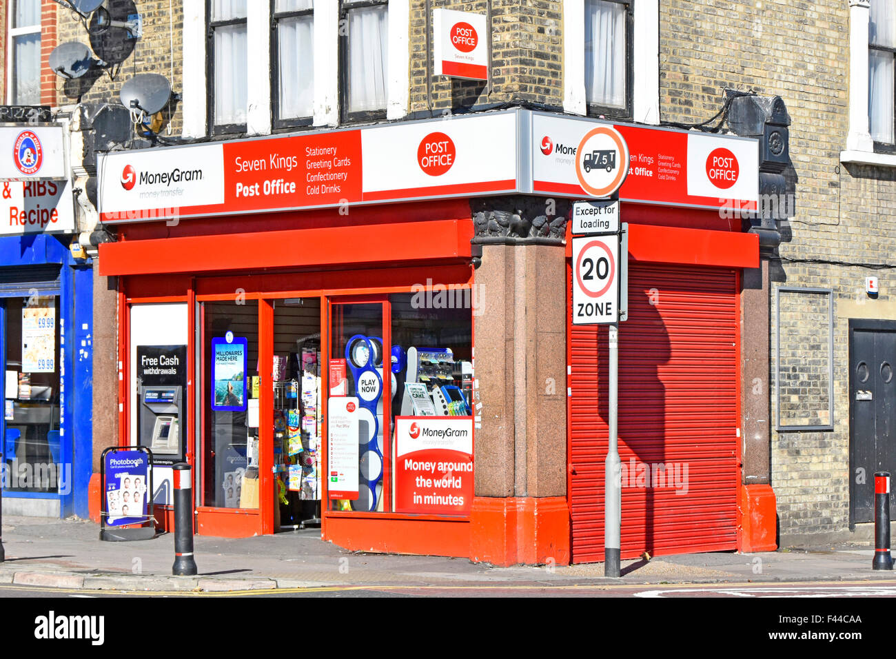 Leuchtend rotes Postbüro, Eckladen mit Geldautomaten im Freien in der Wand im Seven Kings Redbridge East London, England Stockfoto