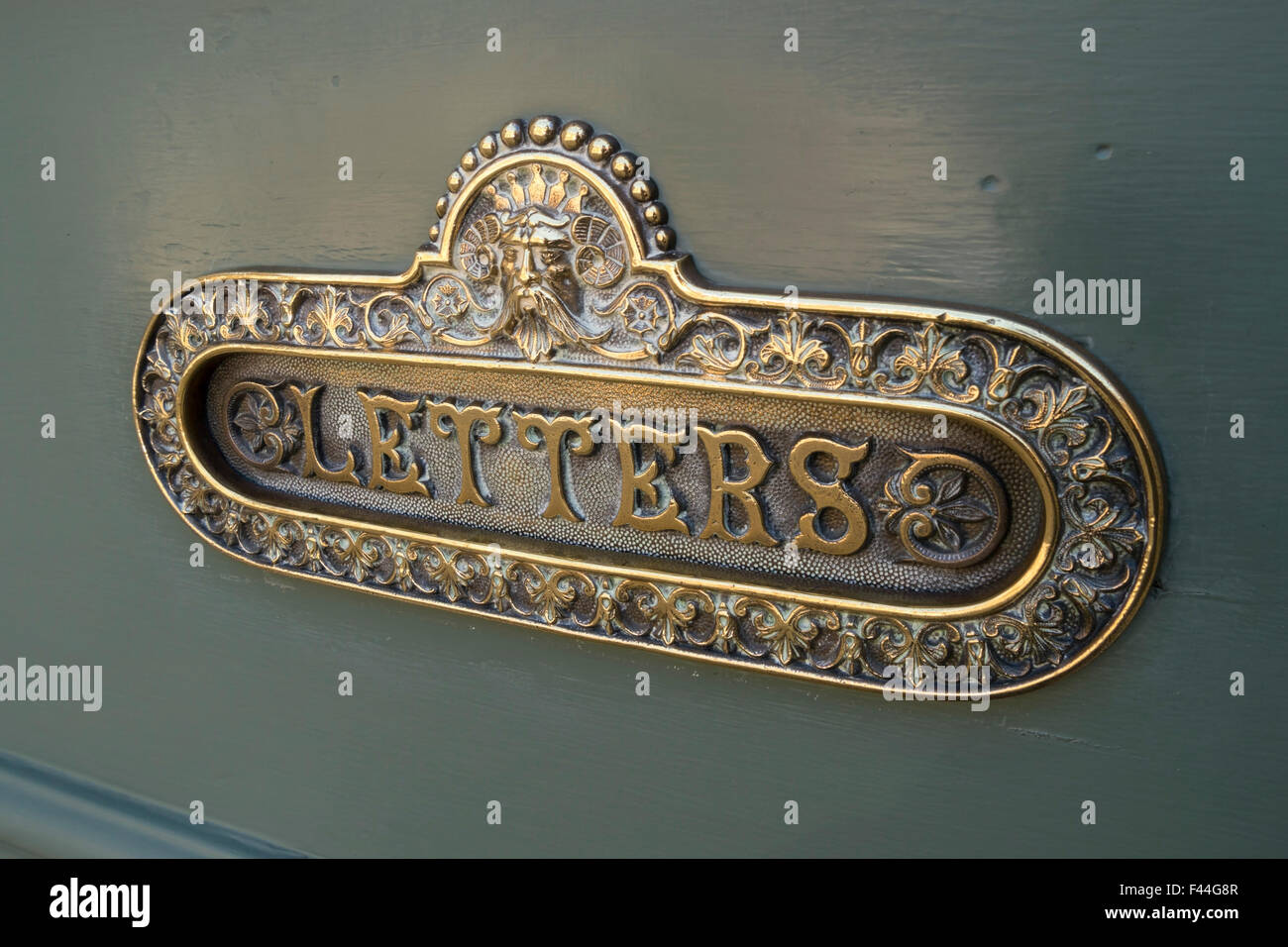 Alt, reich verzierten poliert Messing Briefkasten auf grün bemalte hölzerne Eingangstür, UK. Stockfoto