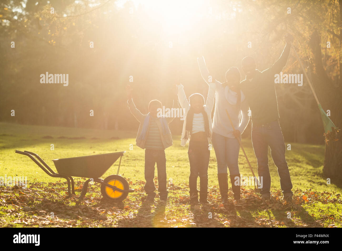 Jung, lächelnd, Familie posieren zusammen mit erhobenen Armen Stockfoto