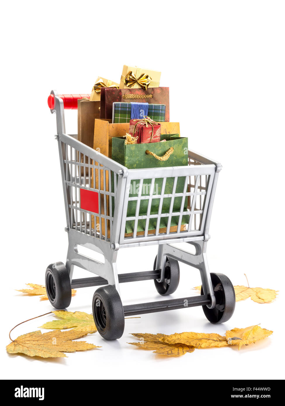 Einkaufswagen voller Taschen voller shopping Elemente mit Laub auf dem Boden als Herbst Verkauf Konzept - Schuss auf weiß Stockfoto