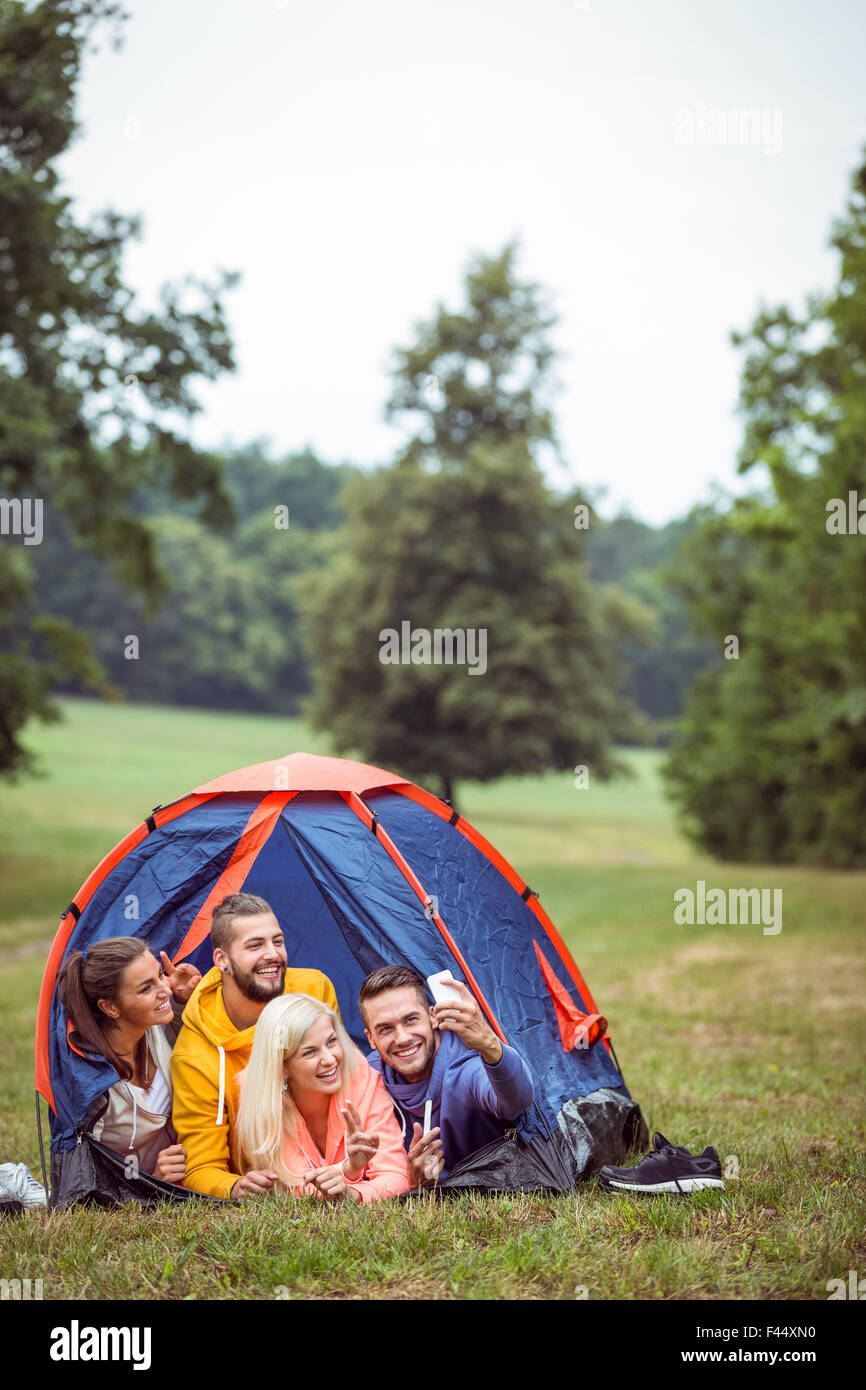 Glückliche Freunde liegen in ihrem Zelt nehmen selfie Stockfoto