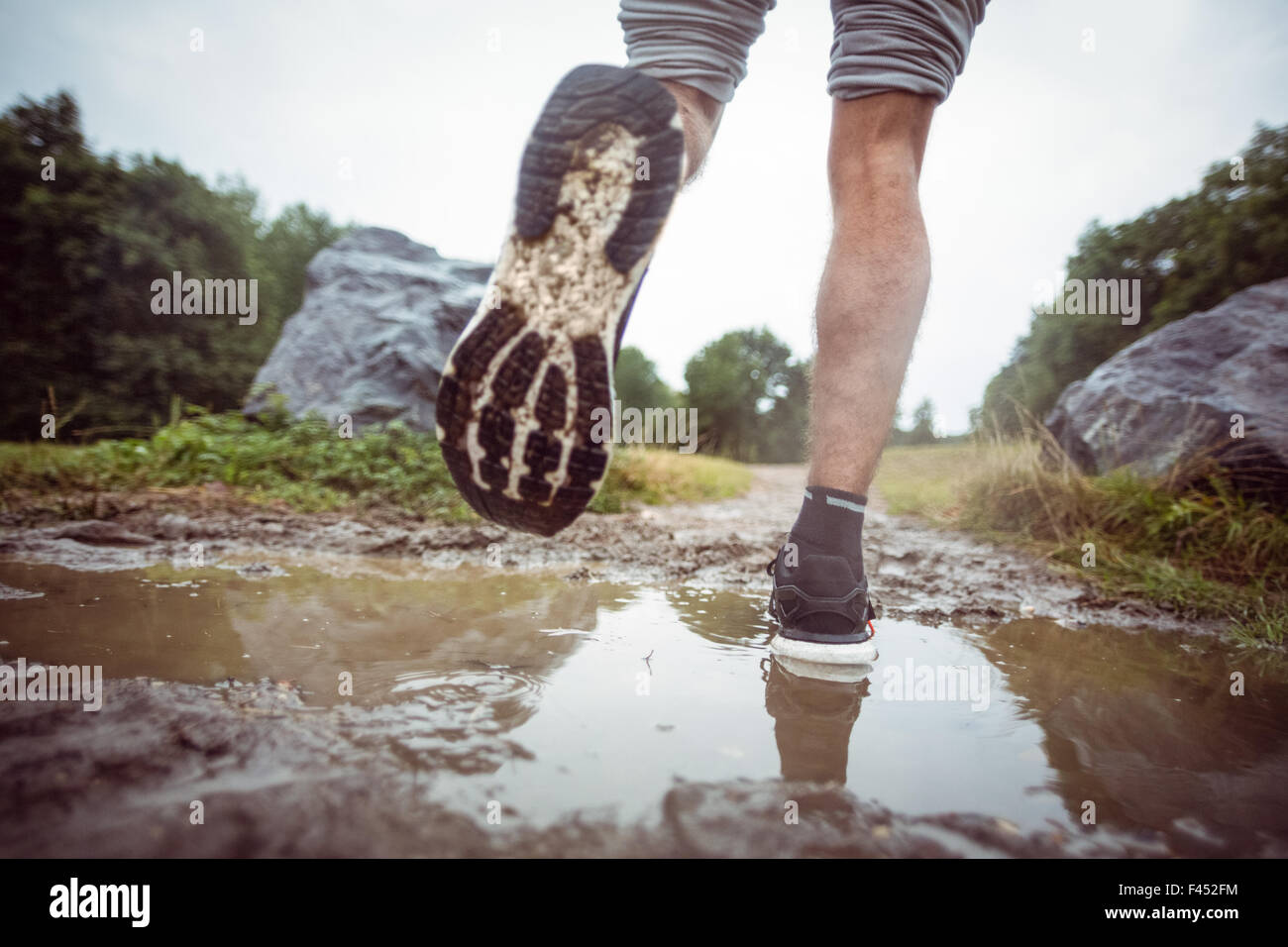 Mann durch Schlammpfützen Joggen Stockfoto