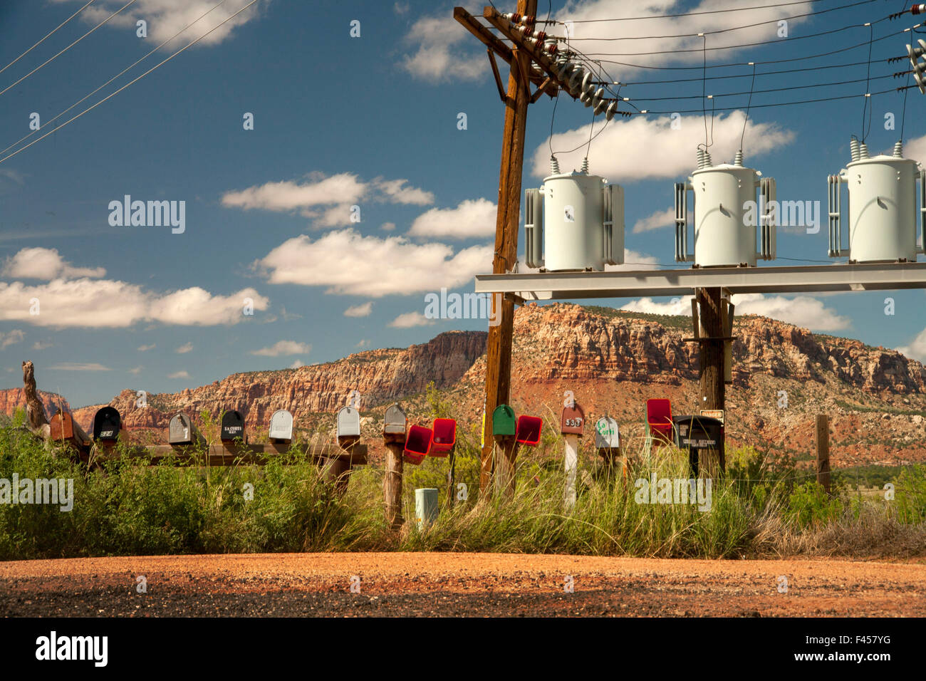 Eine Reihe von nummerierten Postfächer ist mit elektrischen Transformatoren auf einem ländlichen Lane in Cane Betten, AZ. Hinweis Butte im Hintergrund gegenübergestellt. Stockfoto