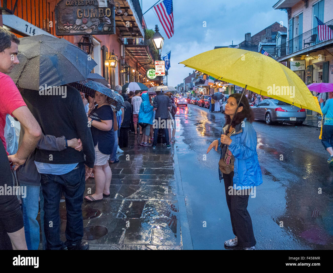 Kauern unter Sonnenschirmen im Regen an St. Peter Street in New Orleans, warten jazz-Liebhaber in der Schlange der Stadt berühmte Preservation Hall musikalische Ort eingeben. Stockfoto