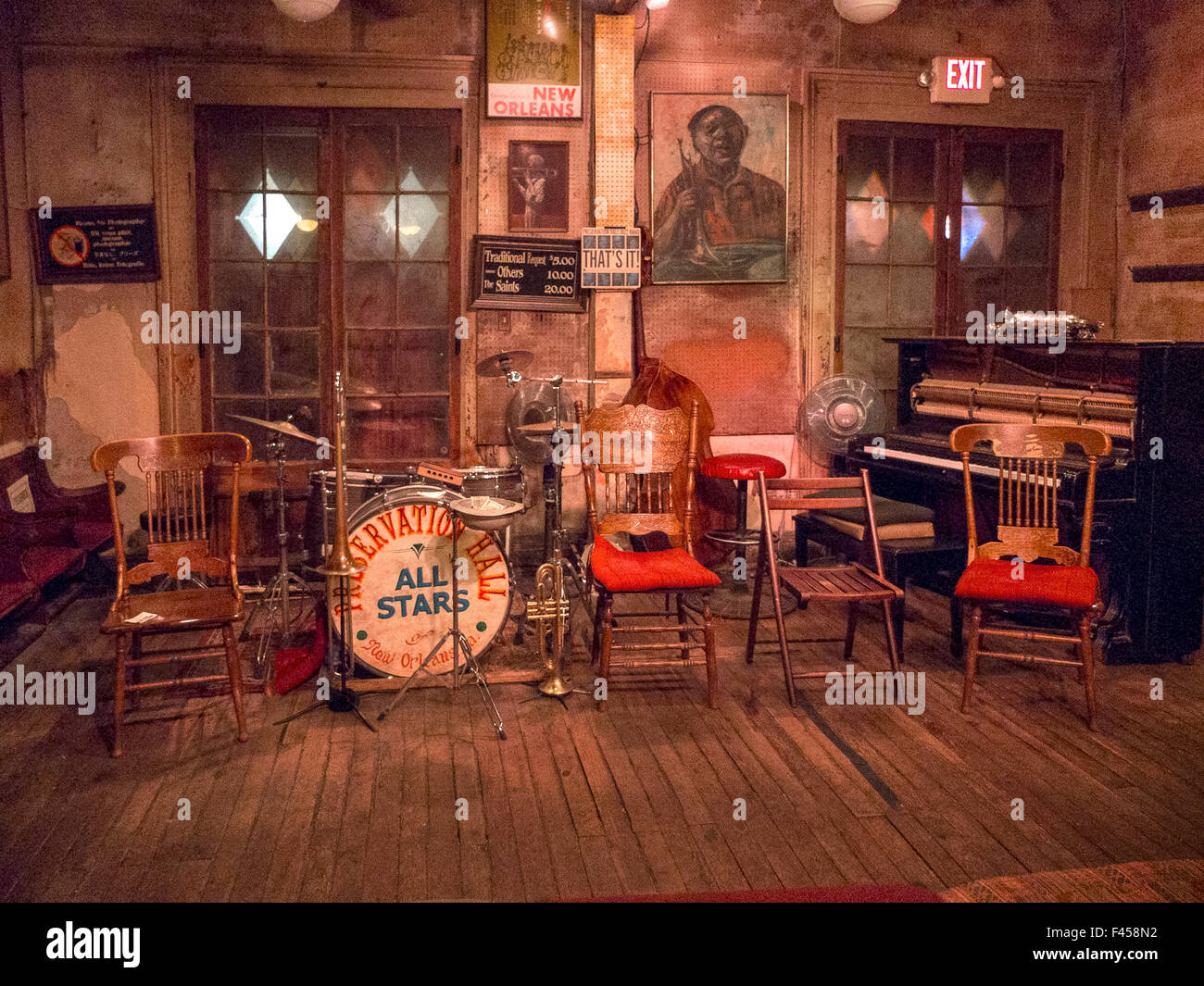 Musikinstrumente und alte Stühle an den berühmten French Quarter jazz Veranstaltungsort Preservation Hall in New Orleans, Louisiana Beachten Sie die Zeichen mit den Preisen für Publikum Anfragen und Porträtmalerei an Wand. Stockfoto
