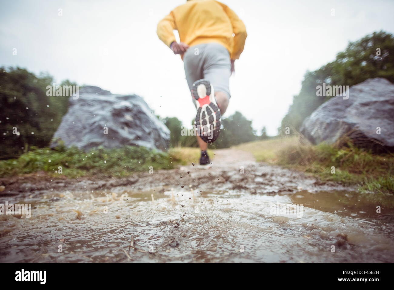 Mann durch Schlammpfützen Joggen Stockfoto