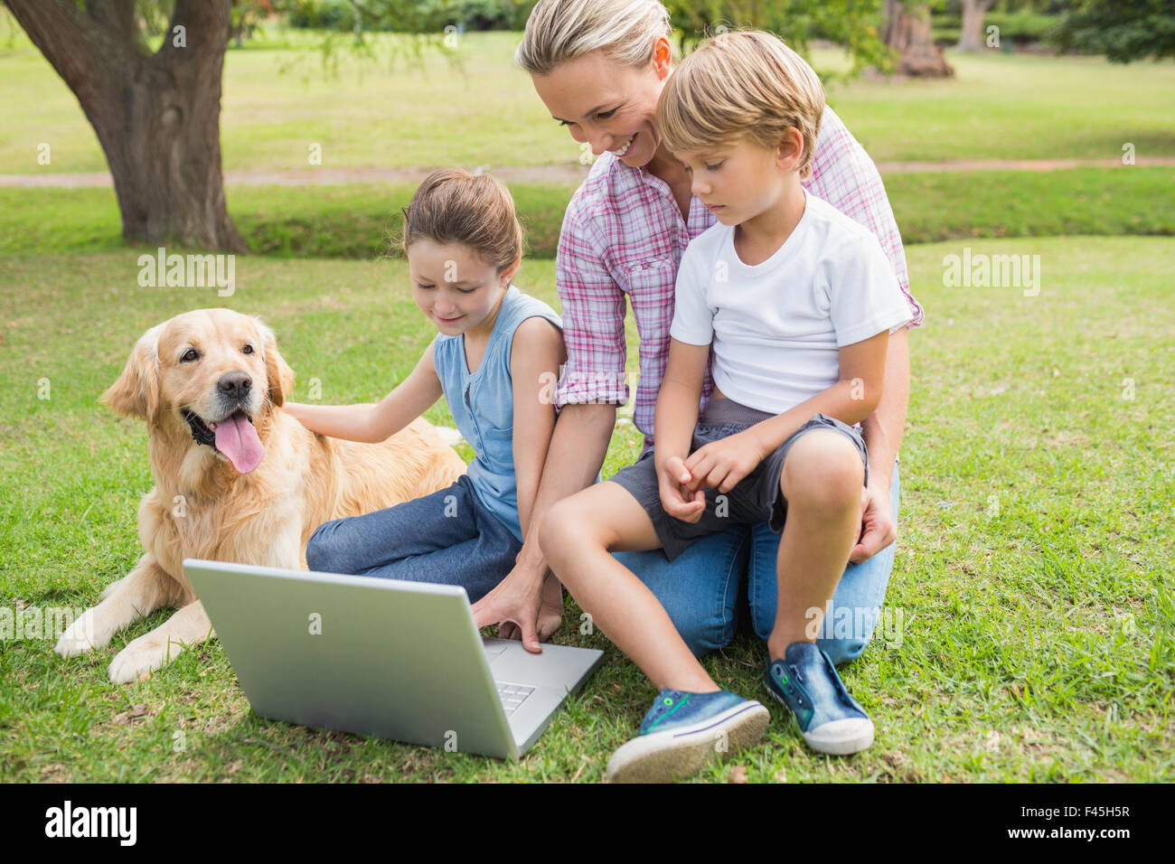 Glückliche Familie mit ihrem Hund mit laptop Stockfoto
