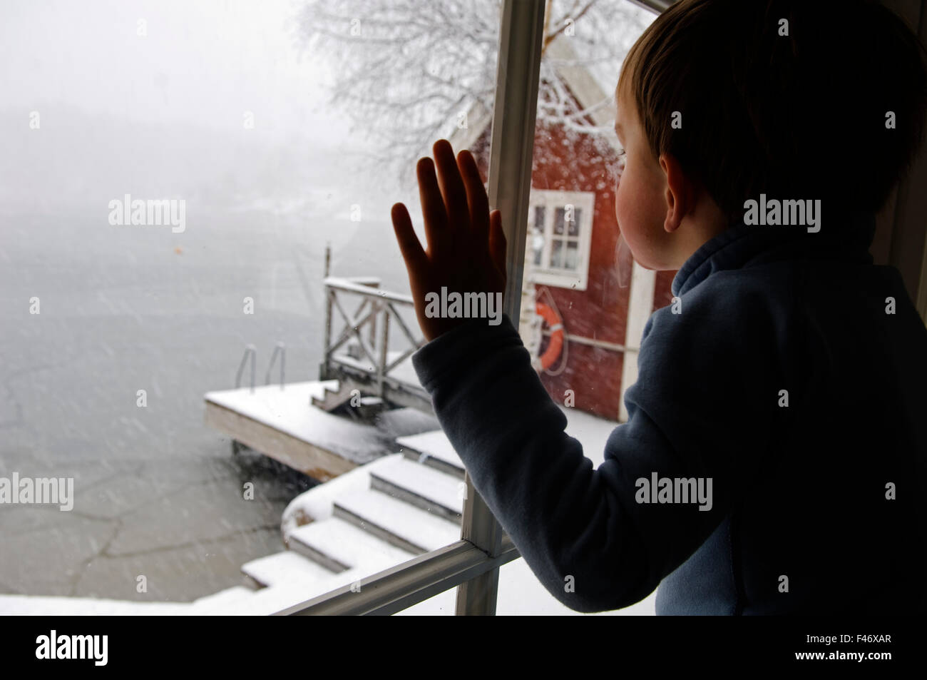 Ein Kind aus einem Fenster ein Wintertag, Schweden. Stockfoto