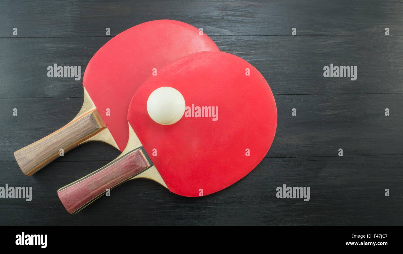 Paar rote Tischtennisschläger auf dunklem Hintergrund mit Exemplar Stockfoto
