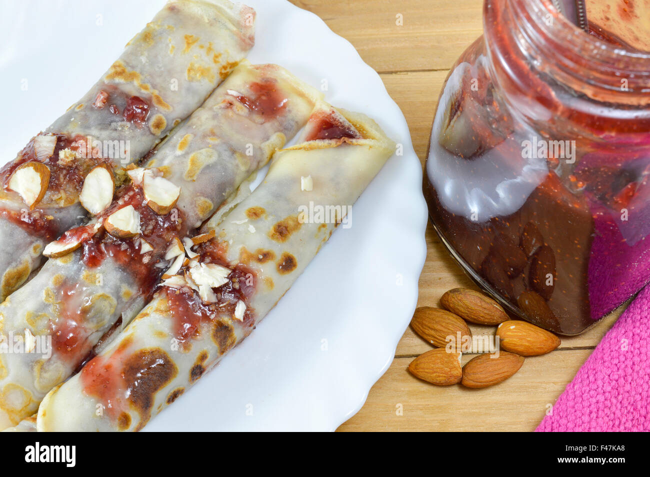 Süße Pfannkuchen mit Erdbeer Konfitüre und Haselnüsse auf den Teller serviert Stockfoto